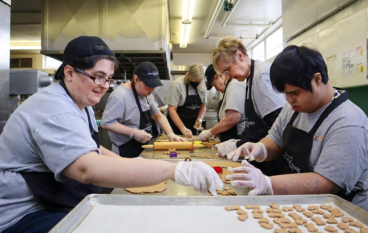 Beyond Bones employees working together around a counter in a industrial kitchen to make dog treats.