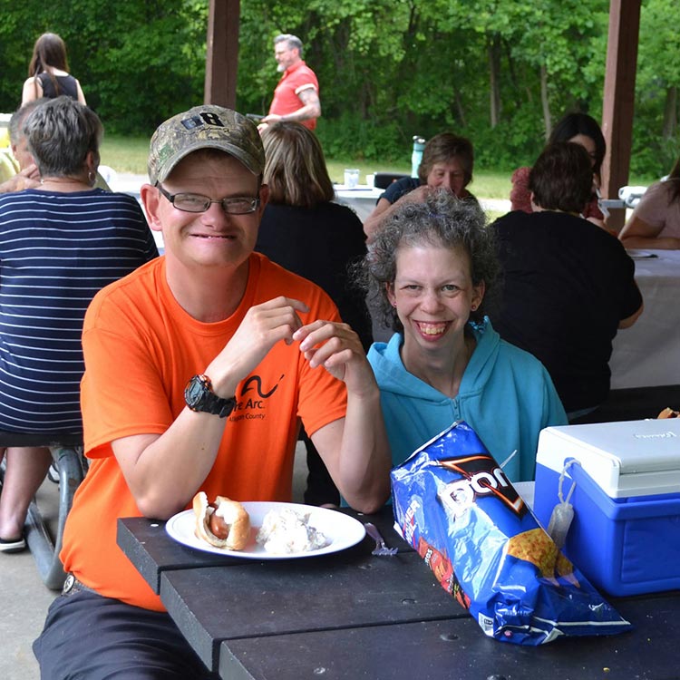 Two Arc of Allegan members and Beyond Bones employees enjoy a picnic lunch at an Arc of Allegan event.