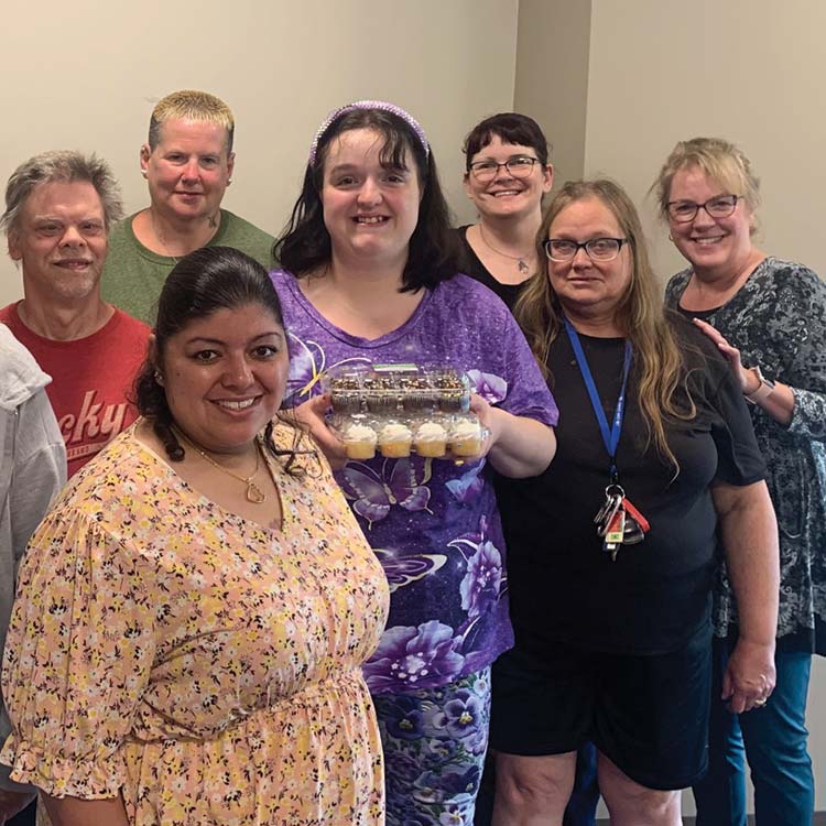 a group of arc members posing together with a tray of cupcakes